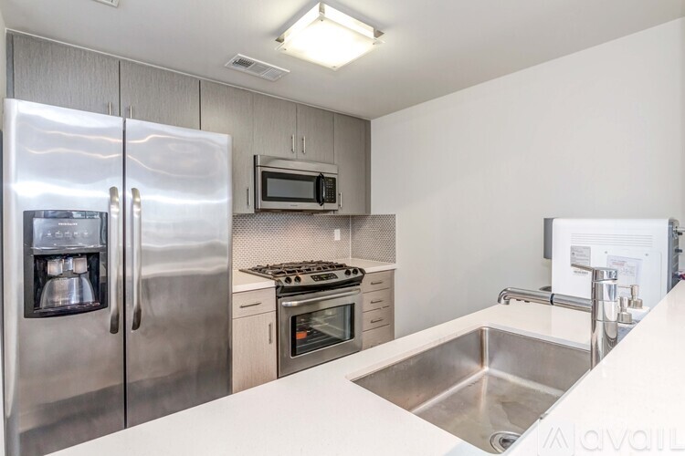 A kitchen with a stainless steel refrigerator, microwave, oven, and sink.
