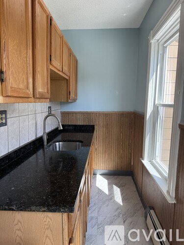 A kitchen with wooden cabinets and a black countertop.