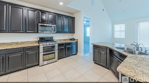 A kitchen with black cabinets and a granite countertop.