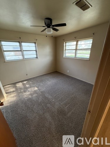 A room with a ceiling fan and two windows.