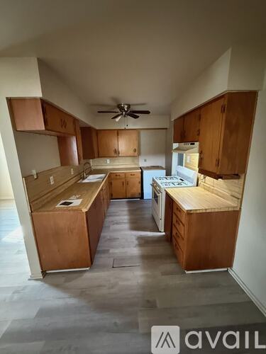 A kitchen with wooden cabinets and a ceiling fan.