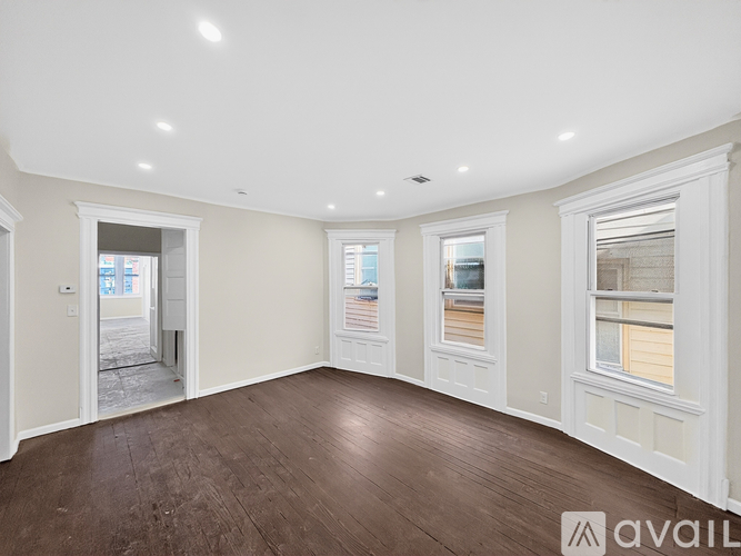 A spacious room with wooden floors and white walls.