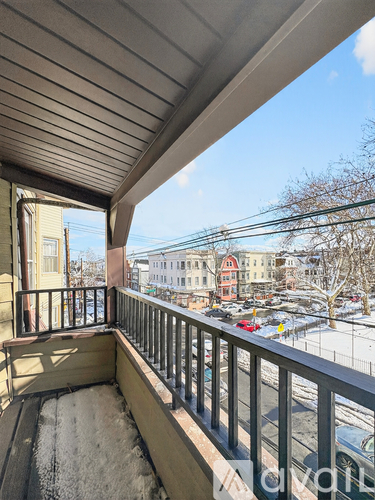 A balcony with a view of a snowy street and buildings.