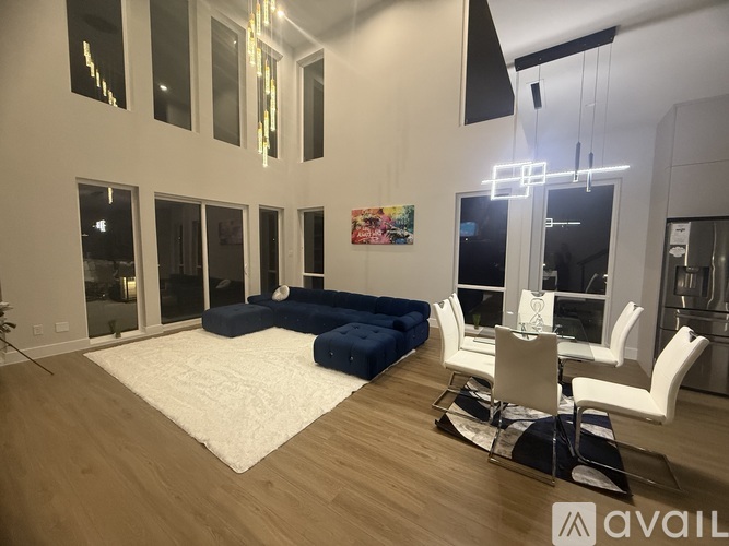 A modern living room with a white rug and blue ottoman.
