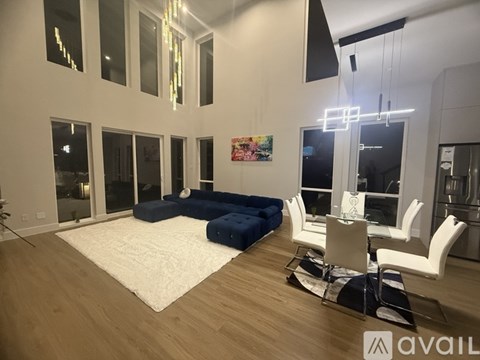 A modern living room with a white rug and blue ottoman.