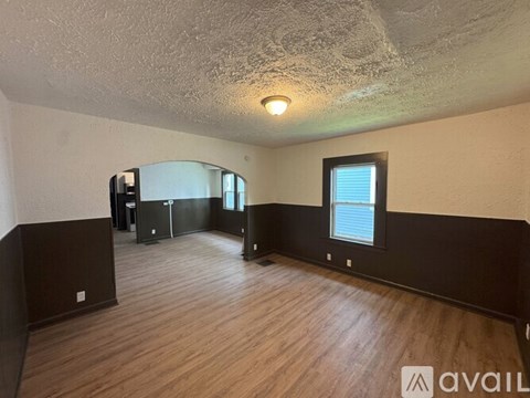 A room with wooden floors and a window with blinds.