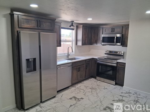 A kitchen with a marble floor and a refrigerator on the left.
