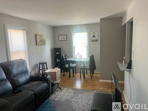 A living room with a black couch and a dining table with chairs.
