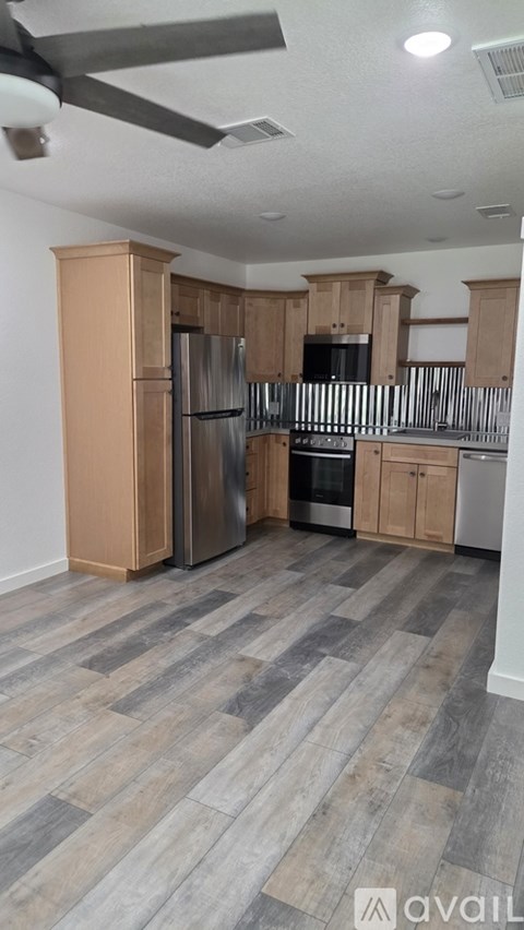 A kitchen with wooden cabinets and a grey floor.