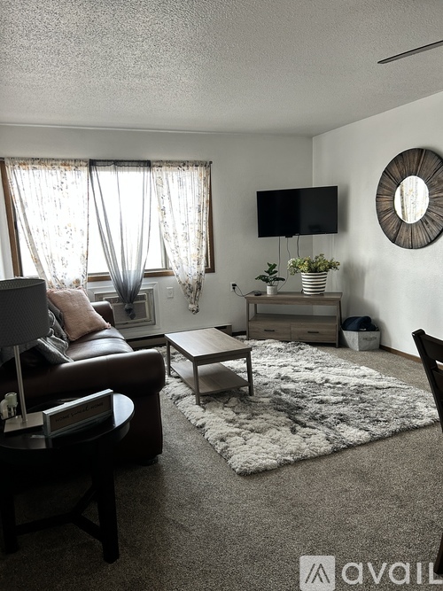 A living room with a brown leather chair, a white rug, and a flat screen TV mounted on the wall.