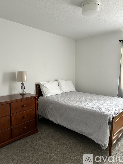 A bedroom with a bed, nightstand, and lamp.