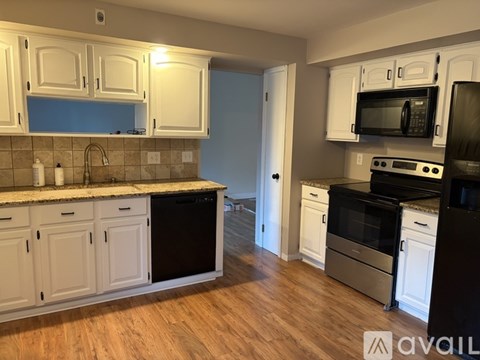 A kitchen with white cabinets and black appliances.