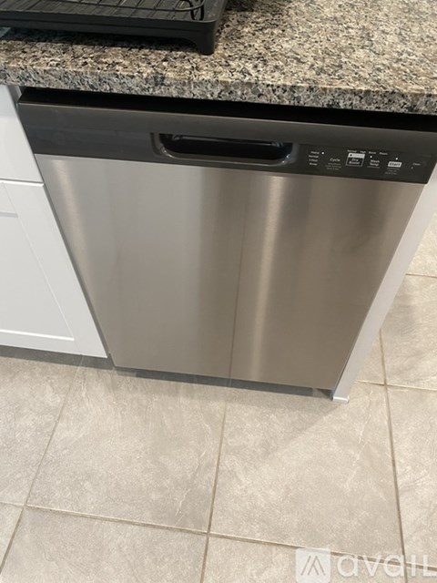 A stainless steel dishwasher with a black top rack sits on a kitchen counter.