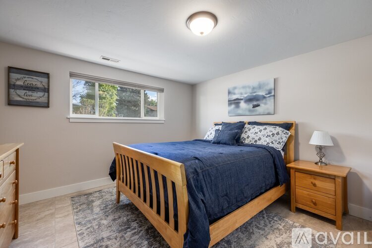 A bedroom with a bed, nightstand, and window.