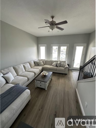 A living room with a long couch and a ceiling fan.