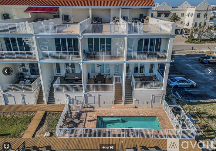 A large white building with a pool in the middle of a wooden deck.