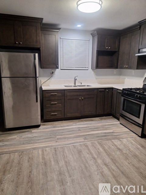 A kitchen with wooden cabinets and a stainless steel refrigerator.