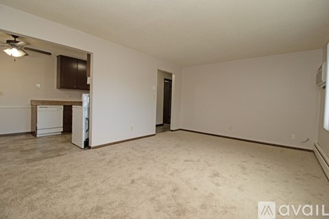 A spacious room with beige carpeting and a ceiling fan.