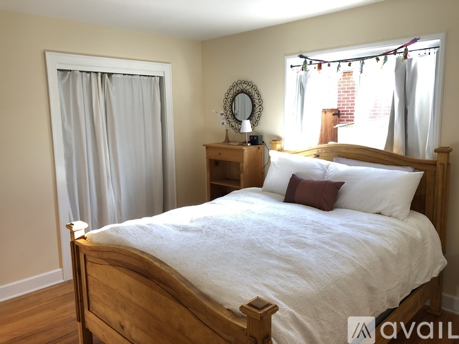 A bedroom with a large bed, wooden furniture, and a window with curtains.