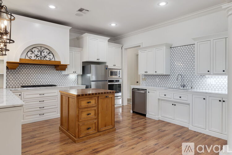 A kitchen with white cabinets and a wooden island.