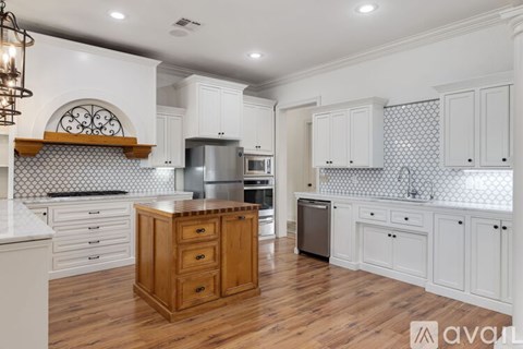 A kitchen with white cabinets and a wooden island.