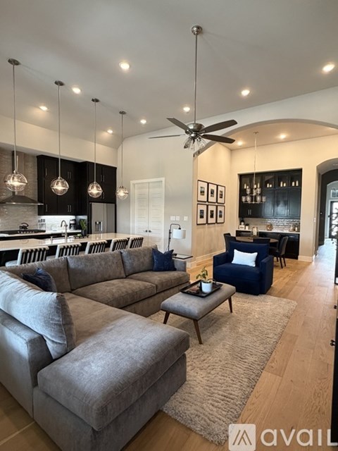 A modern living room with a grey sectional sofa and a dark kitchen area.
