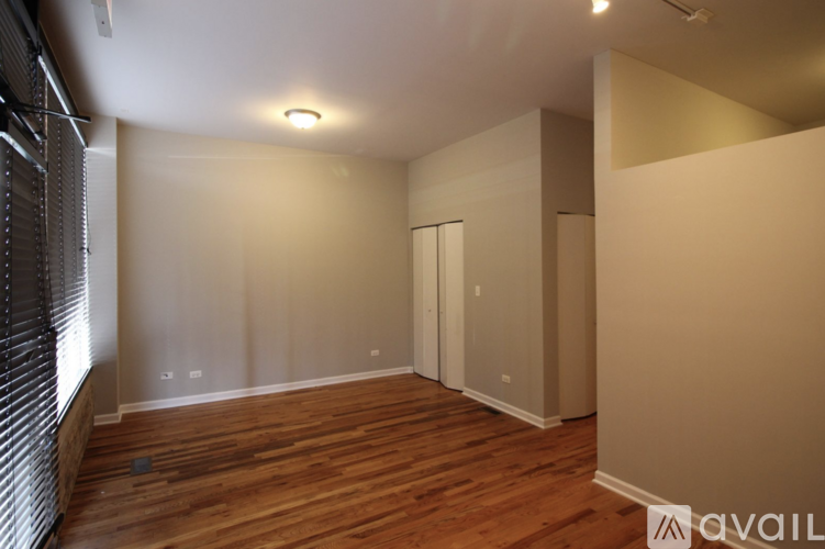 A room with wooden floors and white walls, with a window on the left side.