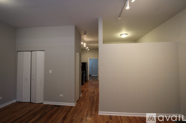 A room with wooden floors and white walls, with a door on the right side.