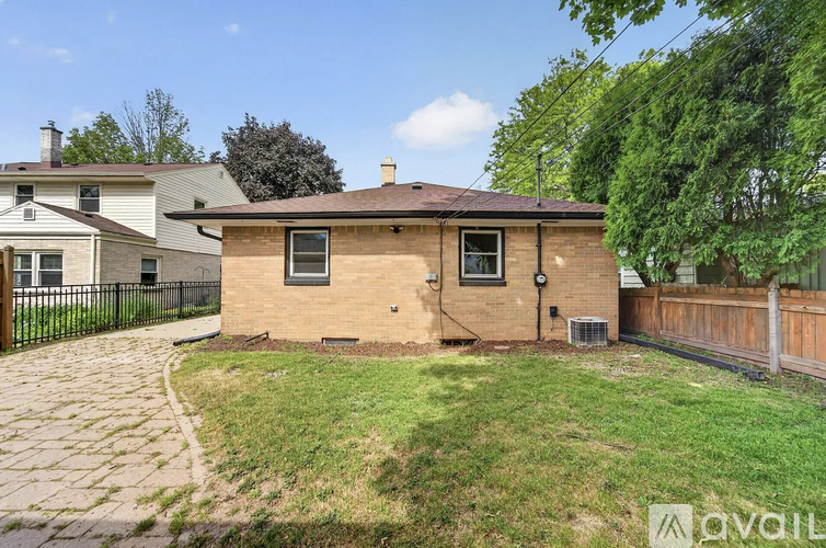 A house with a brick exterior and a black fence is for sale.