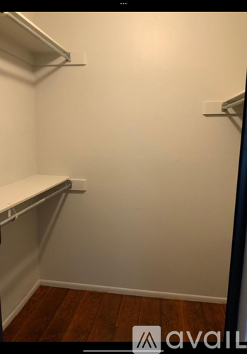 A small, empty room with white walls and wooden flooring.