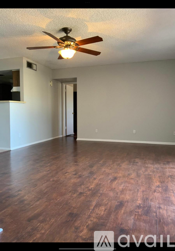 A room with a ceiling fan and wooden flooring.