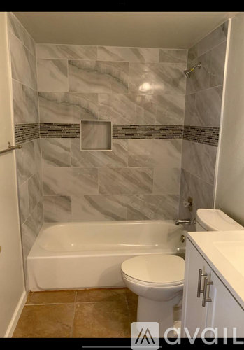 A bathroom with a marble tile shower and a white bathtub.