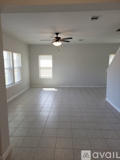 A spacious room with a ceiling fan and tiled flooring.