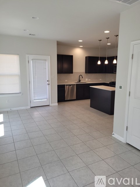 A kitchen with black cabinets and a white door.