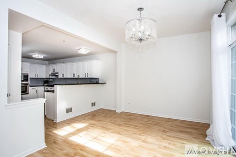 A well-lit kitchen with wooden floors and a chandelier.