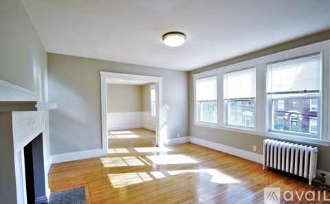 A living room with a fireplace and a window with a view of a city.