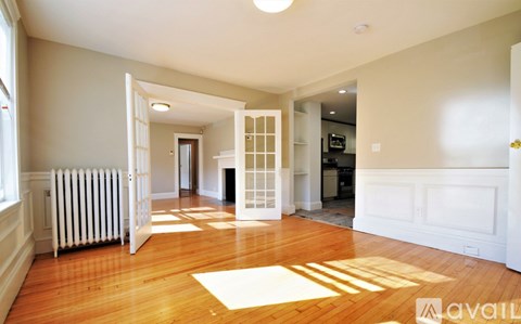 A spacious room with wooden floors and white walls.