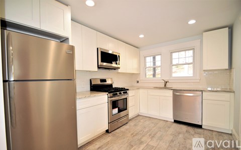 A kitchen with a stainless steel refrigerator and white cabinets.