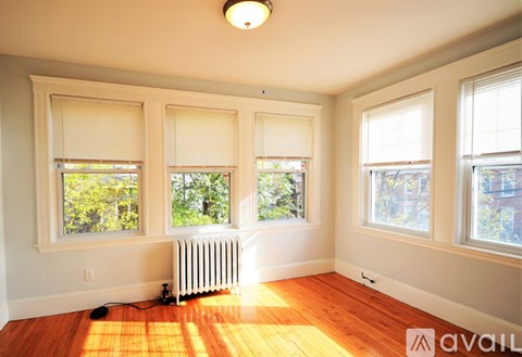 A room with wooden floors and three windows with blinds.