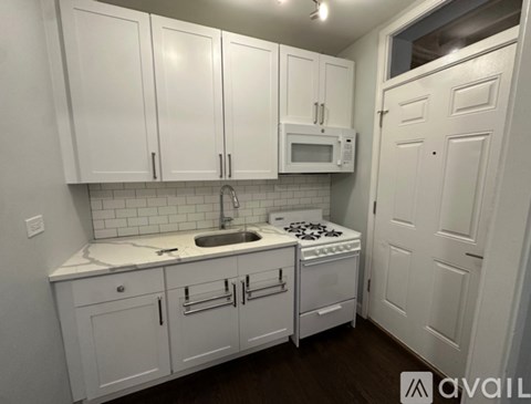 A kitchen with white cabinets and appliances.