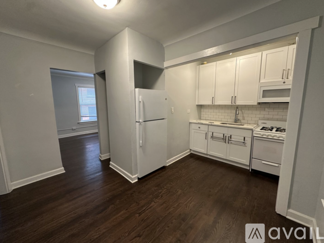 A kitchen with white cabinets and a refrigerator.
