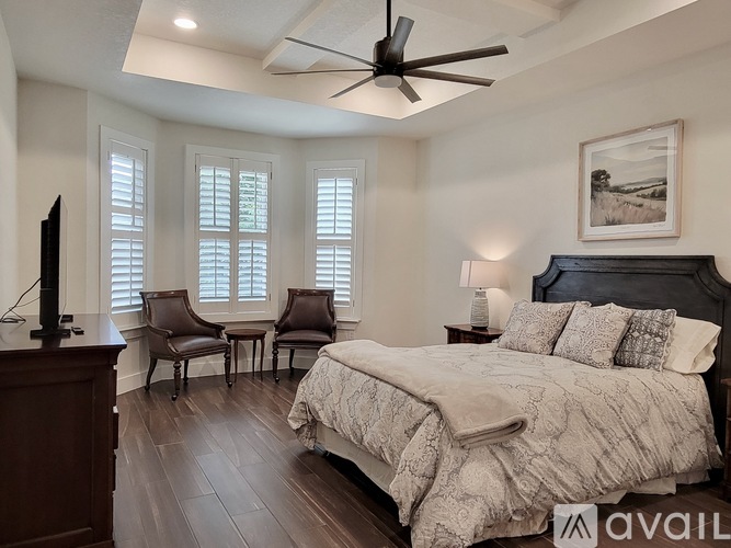 A bedroom with a large bed, a chair, and a ceiling fan.
