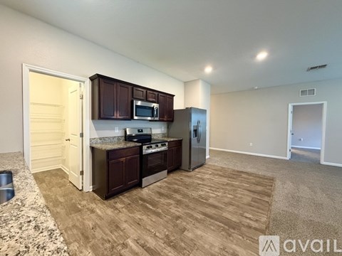 A kitchen with brown cabinets and appliances in a room with a carpeted floor.