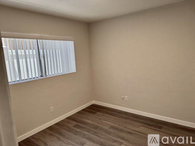 A room with a window and wooden flooring is available for rent.