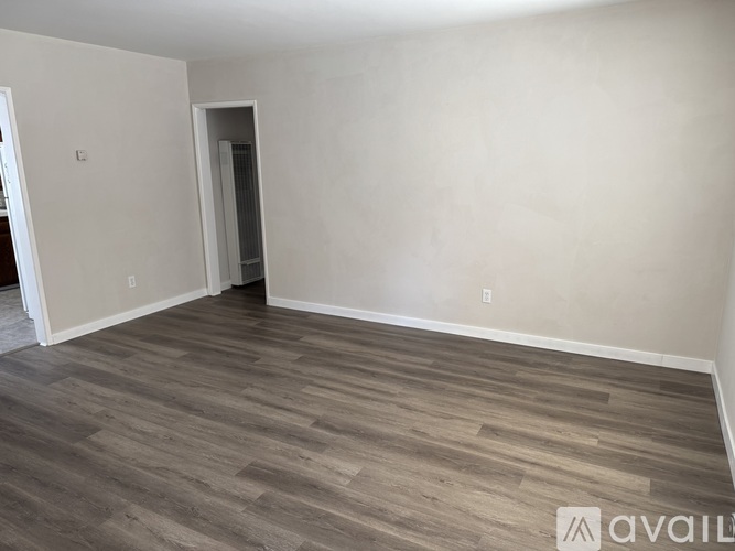 A room with wooden flooring and a doorway leading to another room.