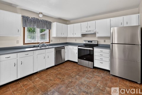 A kitchen with white cabinets and a tiled floor.