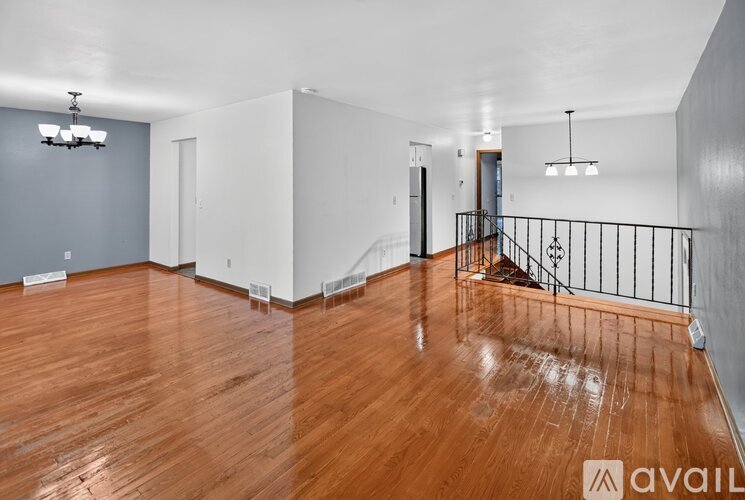 A spacious room with wooden floors and a staircase with a metal railing.