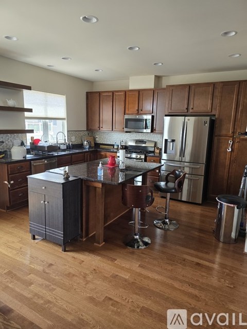 A kitchen with wooden cabinets and a black island.