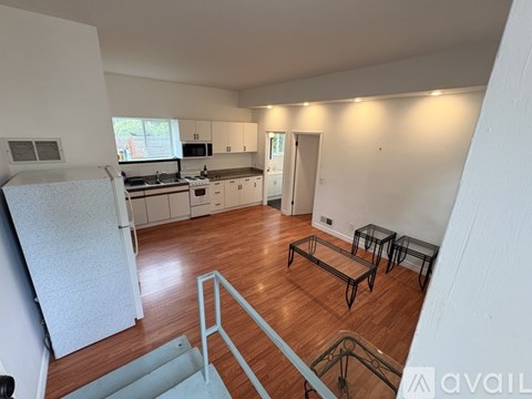 A kitchen with white cabinets and a wooden floor.