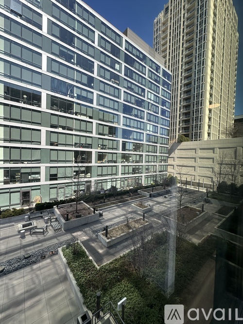 A modern building with a glass facade and a courtyard in front.